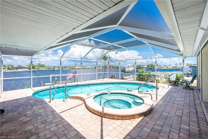View of pool with boat lift, a patio area, a water view, and a dock