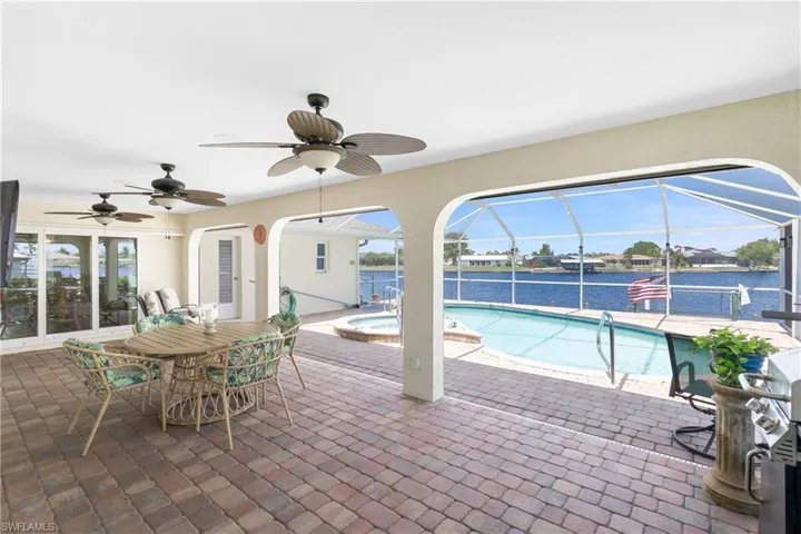Swimming pool with an in-ground hot tub, a patio, a ceiling fan, a lanai, and a water view