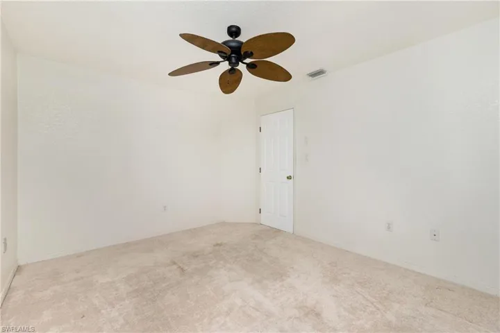 Carpeted spare room with ceiling fan and baseboards