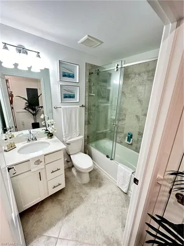 Full bathroom featuring vanity, combined bath / shower with glass door, toilet, and tile patterned floors