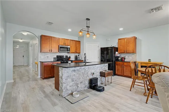 Kitchen featuring dark countertops, brown cabinetry, backsplash, pendant lighting, and recessed lighting