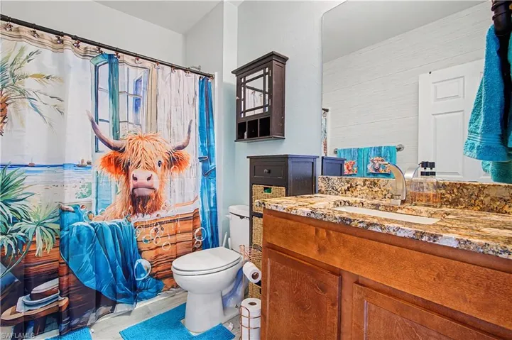 Bathroom featuring curtained shower, vanity, and light wood-style floors