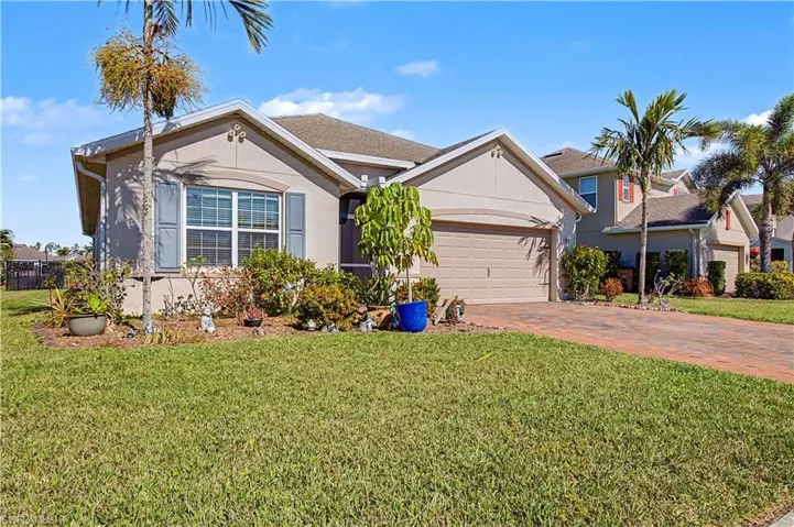 View of front of home featuring stucco siding, a front yard, driveway, and a garage