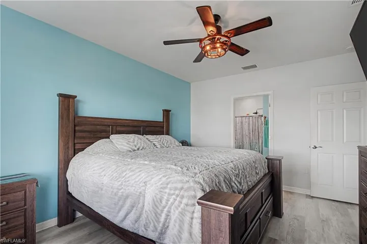 Bedroom featuring light wood-style floors, a ceiling fan, and ensuite bathroom