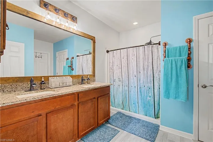 Full bathroom featuring double vanity, a shower and light wood-style flooring