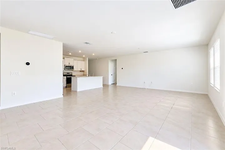 Open-concept interior featuring neutral tile flooring, white cabinetry, a center island, and recessed lighting
