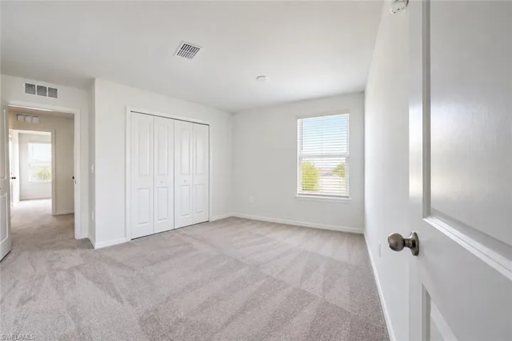 Neutral wall finishes, plush carpeting, multi-panel closet doors, and a window with horizontal blinds
