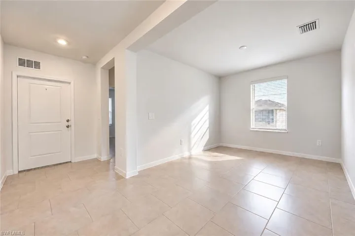 Neutral-toned interior featuring large-format ceramic tile flooring, recessed lighting, and a solid-core paneled entry door