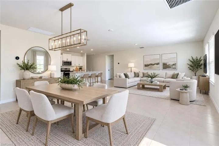 Open-concept interior featuring large-format tile flooring, recessed lighting, and a linear metal pendant light fixture over the dining area