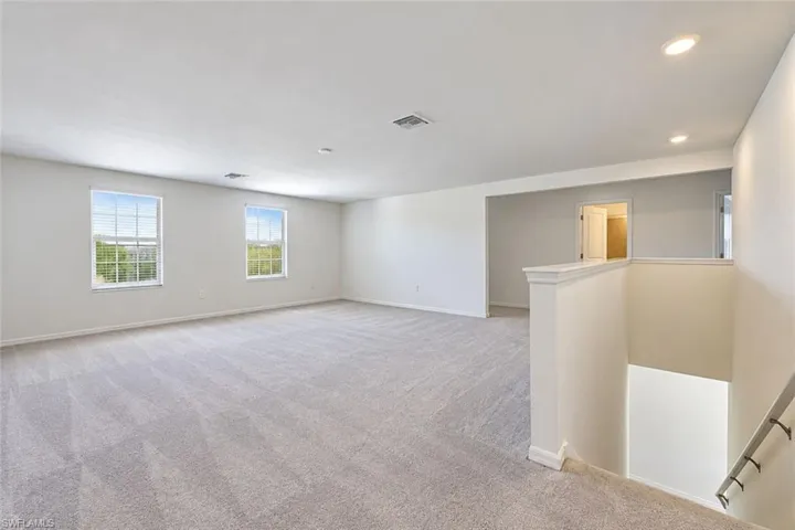Open-concept interior featuring wall-to-wall carpeting, recessed ceiling lighting, and dual windows