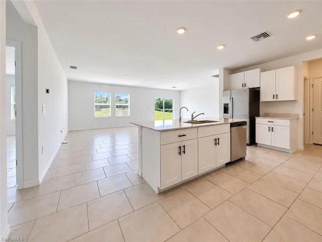 Kitchen featuring a center island, light-toned cabinetry, solid surface countertops, recessed lighting, and tile flooring