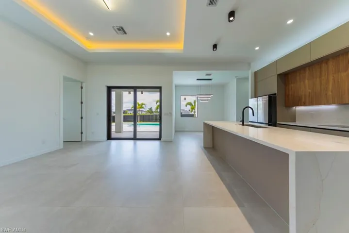 Kitchen featuring modern cabinets, a spacious island, recessed lighting, freestanding refrigerator, and light stone counters