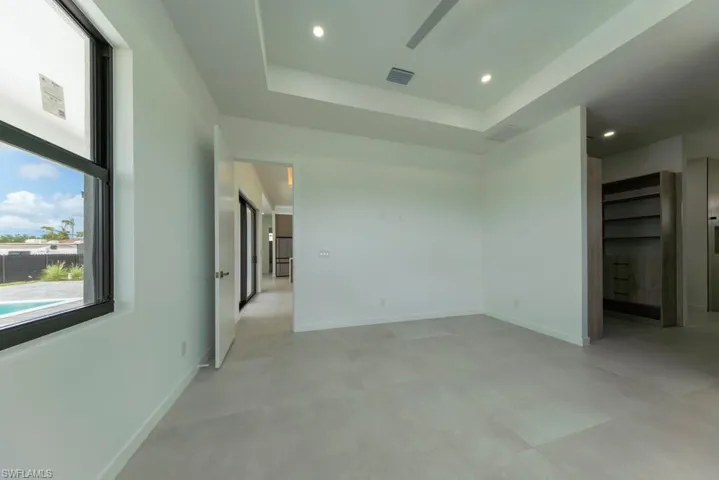 Unfurnished bedroom featuring a tray ceiling and recessed lighting