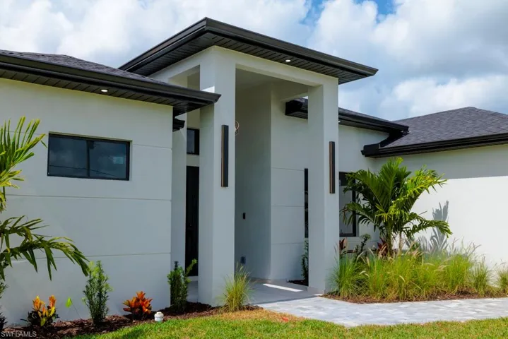 View of exterior entry with stucco siding and roof with shingles