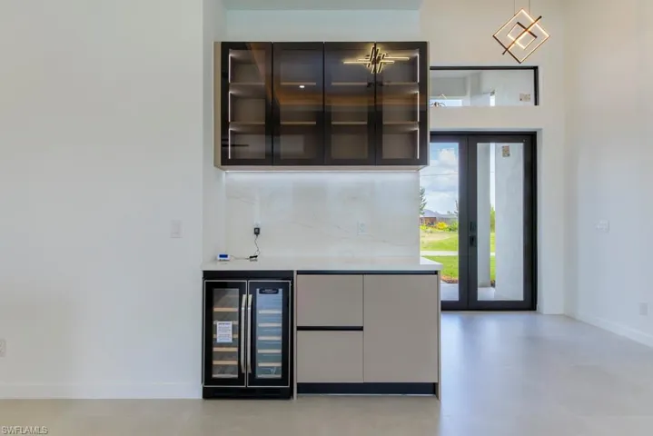 Indoor dry bar with wine cooler and decorative backsplash