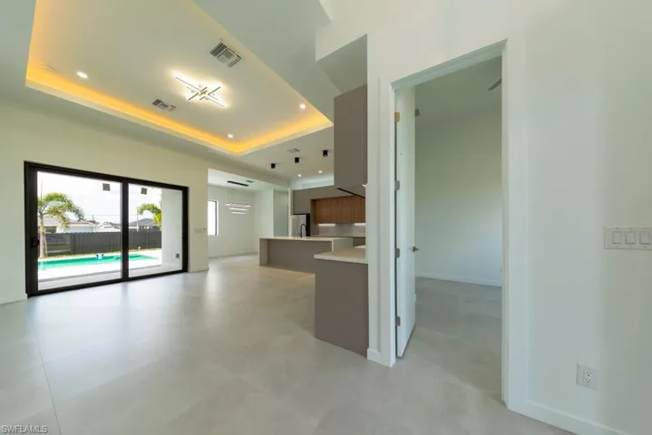 Kitchen featuring modern cabinets, a tray ceiling, light countertops, recessed lighting, and open floor plan