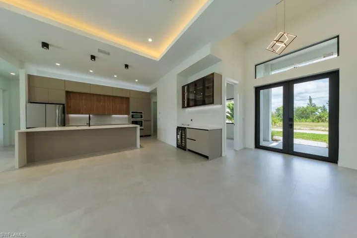 Kitchen with modern cabinets, appliances with stainless steel finishes, light countertops, french doors, and recessed lighting