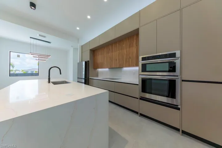 Kitchen with modern cabinets, stainless steel appliances, light stone counters, recessed lighting, and pendant lighting