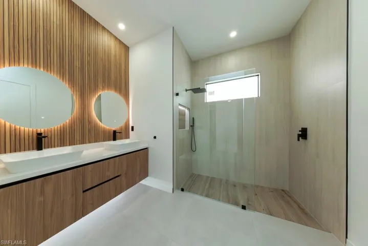 Bathroom with double vanity, a walk in shower, tile patterned flooring, and recessed lighting