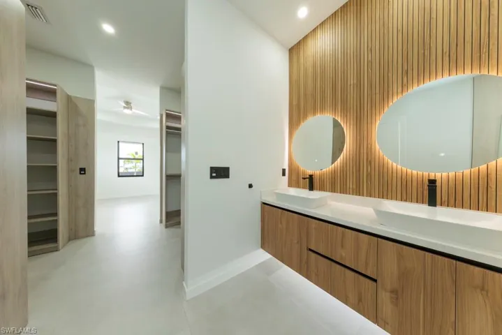 Bathroom with double vanity, a walk in closet, a high ceiling, wooden walls, and recessed lighting