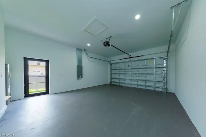 Garage with electric panel, recessed lighting, and a garage door opener