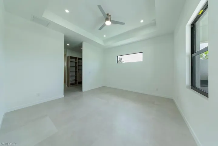 Unfurnished room featuring concrete flooring, a raised ceiling, recessed lighting, and a ceiling fan