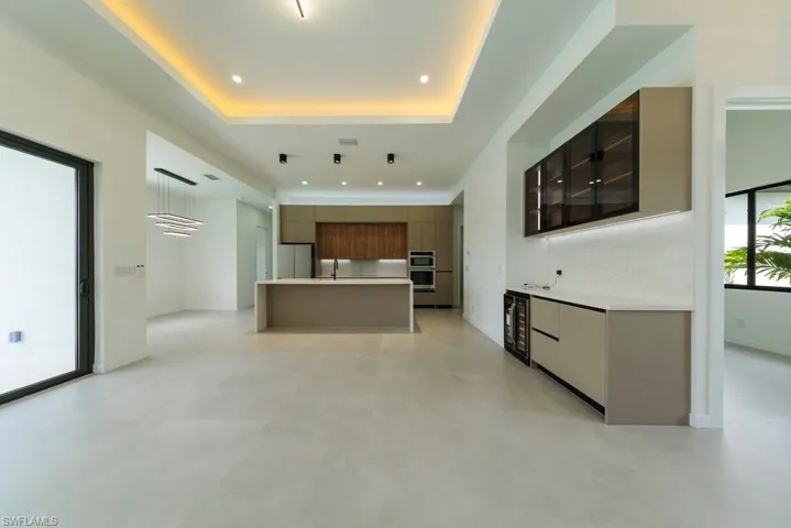 Kitchen with modern cabinets, light countertops, a spacious island, recessed lighting, and freestanding refrigerator