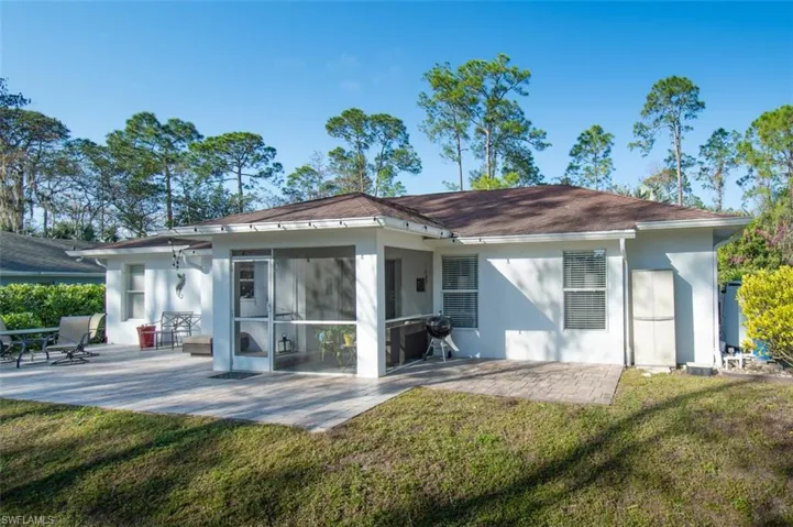 Back of property featuring a patio area, a sunroom, and a lawn