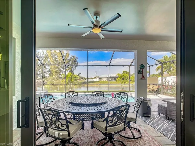 Sunroom with a ceiling fan, a patio, a water view, and outdoor dining space