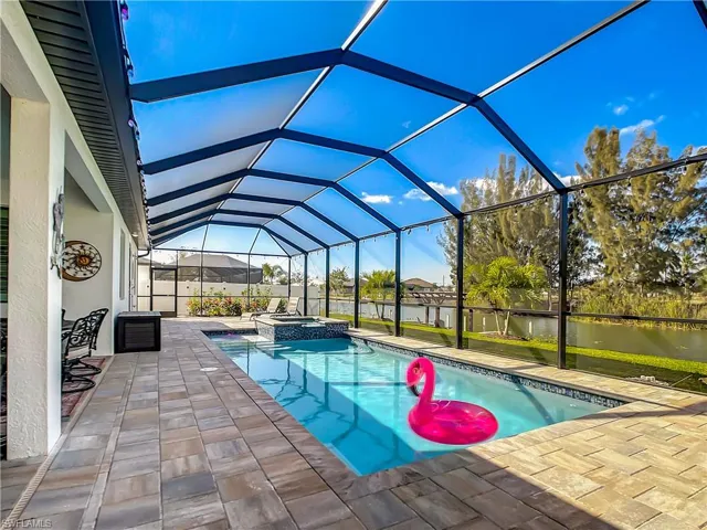 View of swimming pool featuring a water view, a sunroom, a lanai, a pool with connected hot tub, and a patio
