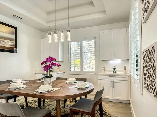 Dining area with a raised ceiling and light wood-type flooring