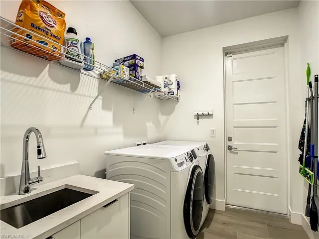 Washroom with light wood finished floors and washing machine and dryer