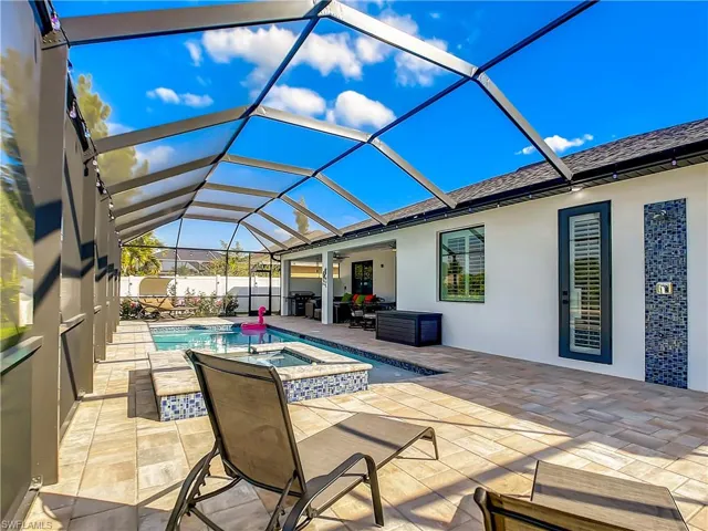 View of swimming pool with a sunroom, a patio area, a pool with connected hot tub, grilling area, and glass enclosure