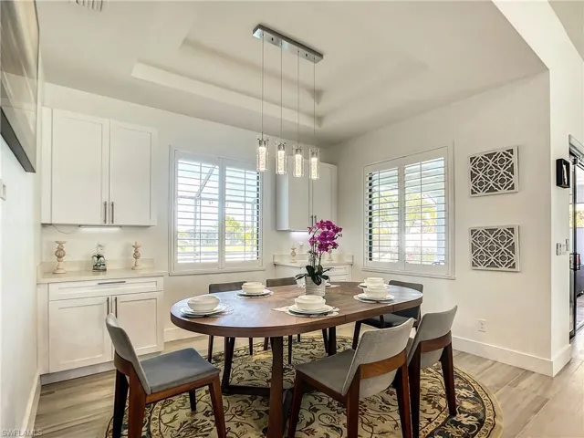 Dining area with a raised ceiling and light wood-style floors