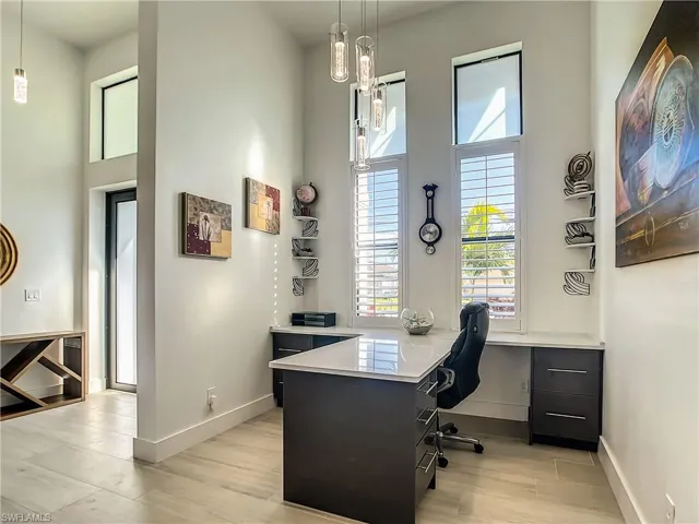 Office space with healthy amount of natural light, light wood finished floors, and a towering ceiling