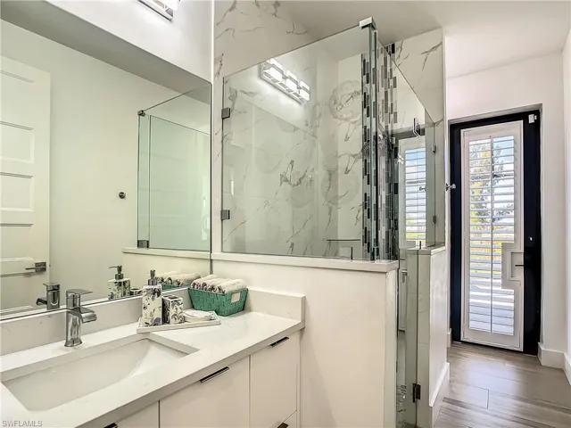 Bathroom featuring a marble finish shower, vanity, and wood finished floors