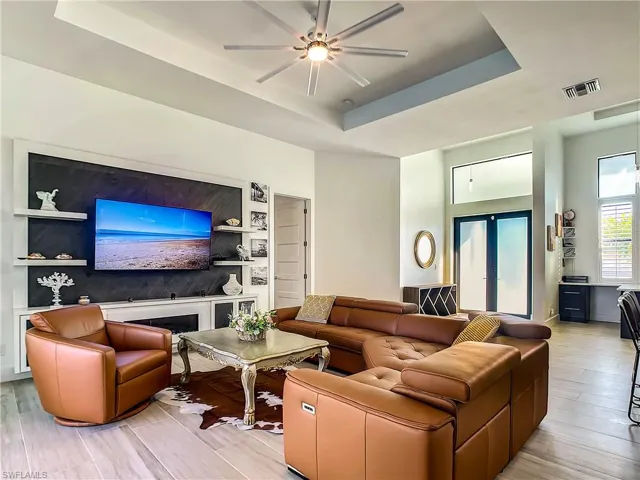 Living area with a tray ceiling, light wood-style floors, and a ceiling fan