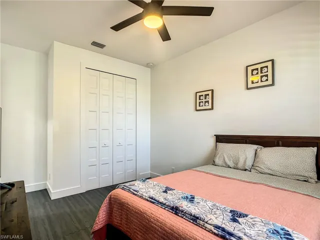 Bedroom featuring dark wood-style flooring, a closet, and ceiling fan