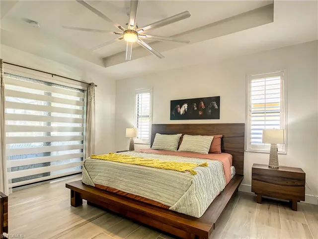 Bedroom featuring a tray ceiling, light wood finished floors, and a ceiling fan