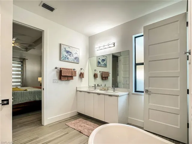 Ensuite bathroom with a soaking tub, double vanity, and light wood-type flooring