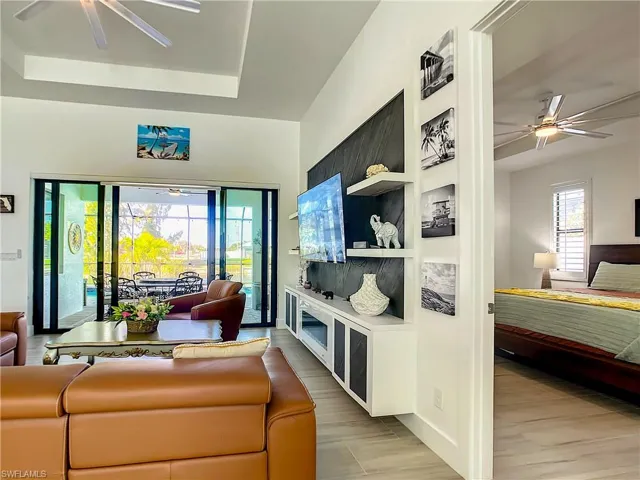 Living area with a ceiling fan, a tray ceiling, light wood-style flooring, and a sunroom