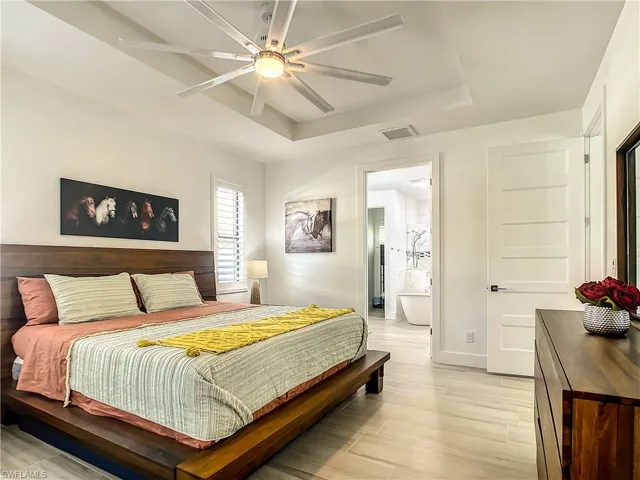 Bedroom featuring a tray ceiling, light wood-style flooring, and ceiling fan