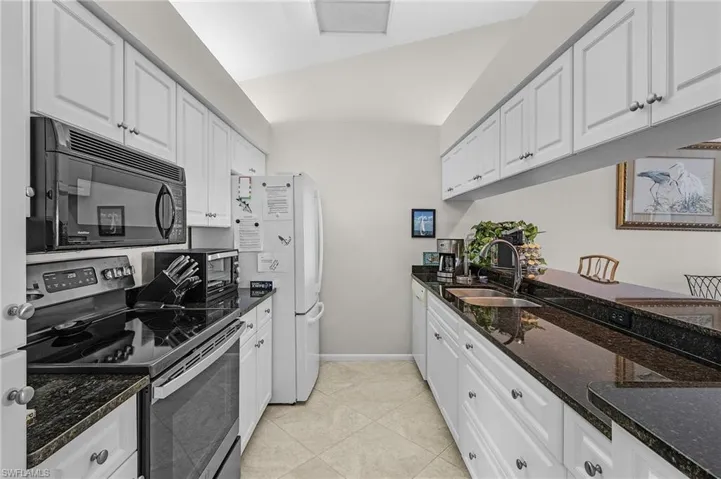 Kitchen featuring dark stone countertops, stainless steel electric range, and white cabinets