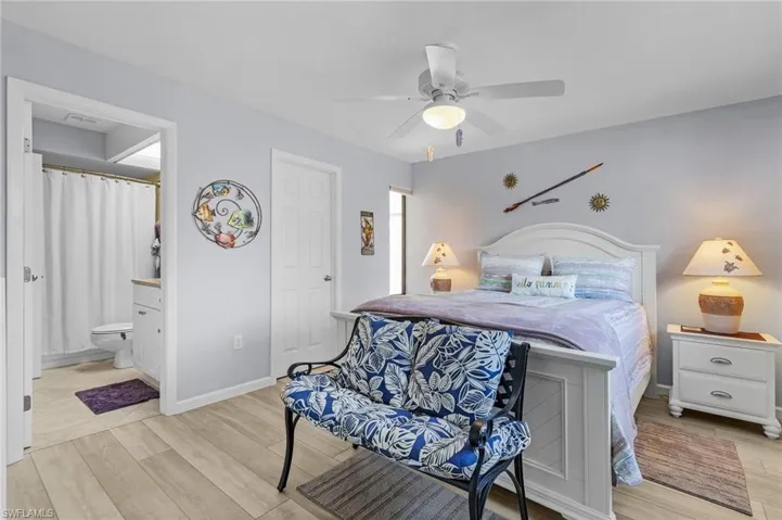 Second bedroom with light hardwood / wood-style flooring, ensuite bathroom, and ceiling fan