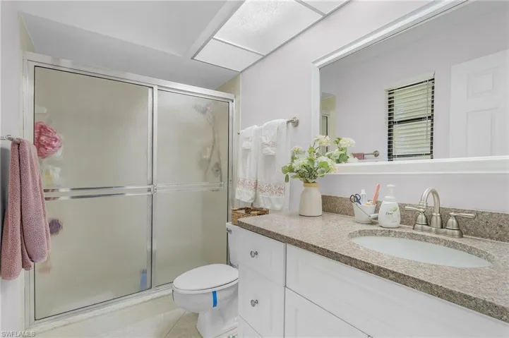 Bathroom featuring vanity, toilet, an enclosed shower, and tile patterned flooring