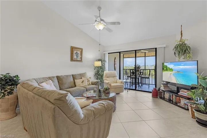 Tiled living room featuring high vaulted ceiling and ceiling fan