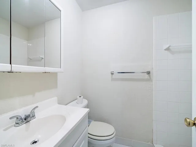 Bathroom with tiled shower, vanity, and toilet