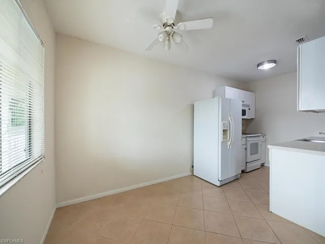 Kitchen featuring white cabinetry, white appliances, light tile patterned floors, sink, and ceiling fan