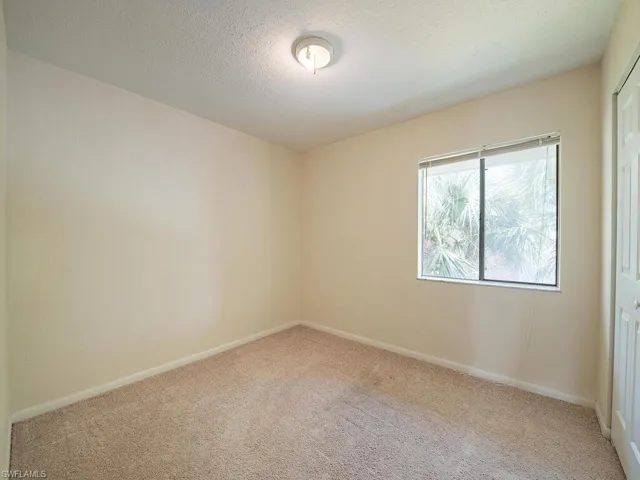 Unfurnished room with light colored carpet and a textured ceiling