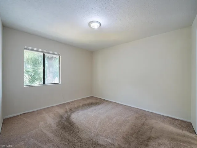 Unfurnished room with a textured ceiling and carpet floors